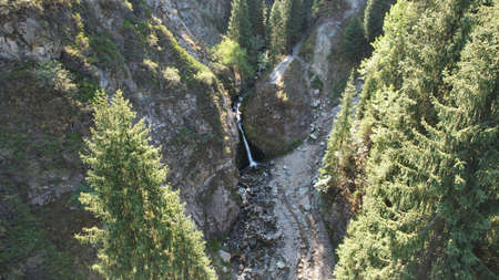 A mountain waterfall in a rocky gorge with forestの写真素材