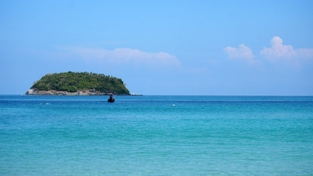 A lonely island in the sea. A boat floats nearbyの写真素材