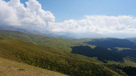 Big white clouds over green hills and mountainsの写真素材
