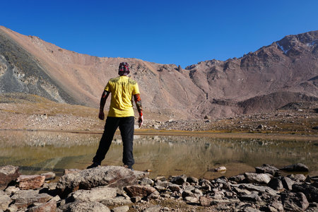 The guy stands epically on shore of mountain lakeの写真素材