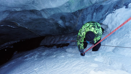 A climber descends into an ice cave in a glacier.の写真素材