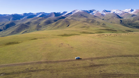 A white SUV rides in the mountains through fieldsの写真素材