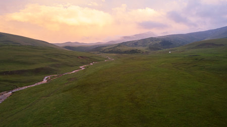 Pink-purple sunset in mountains with green fieldsの写真素材