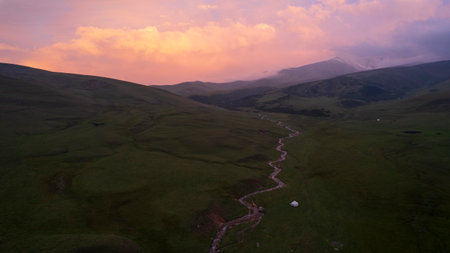 Pink-purple sunset in mountains with green fieldsの写真素材