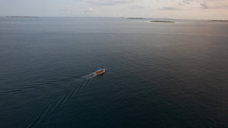 A lonely ship sails into the sea at sunset.の写真素材
