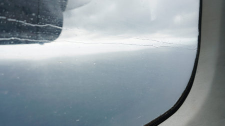 Airplane window showing ocean and clouds during flight