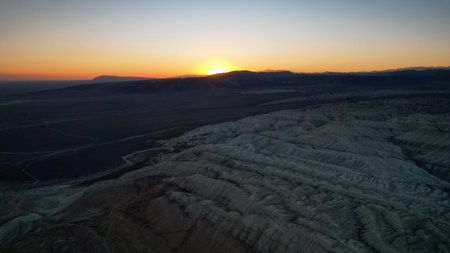Sunset illuminating the vast desert landscape with eroded ridgesの写真素材