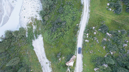 Pickup truck driving on a dirt road near a mountain river