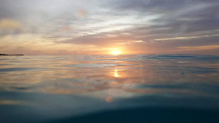 Golden sunrise reflecting on calm ocean waterの写真素材