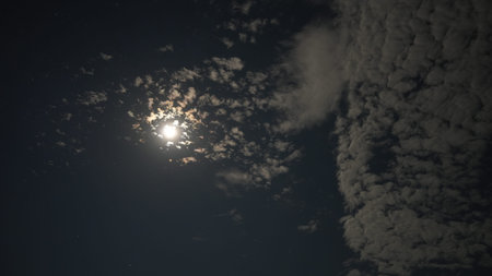 Bright moon shining through scattered clouds at night