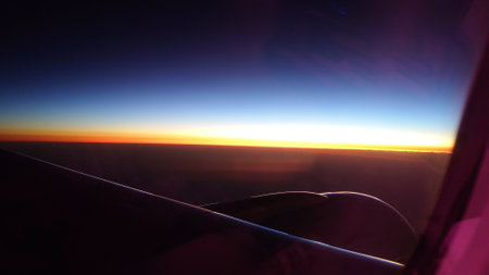 Airplane wing flying high above the clouds during sunsetの写真素材