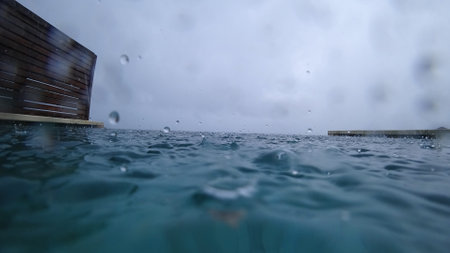 Rain falling on infinity pool overlooking oceanの写真素材