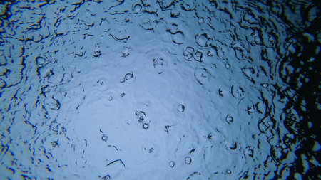 Rain is falling on water surface creating concentric circlesの写真素材