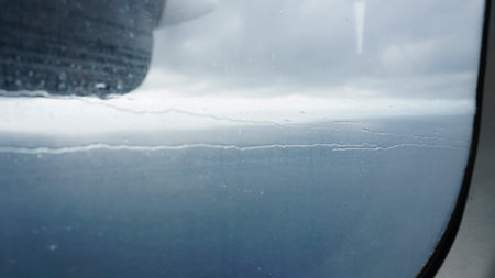 Rain falling on airplane window during flight over ocean