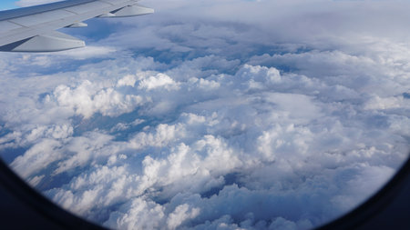 Airplane wing flying over a vast expanse of fluffy white cloudsの写真素材