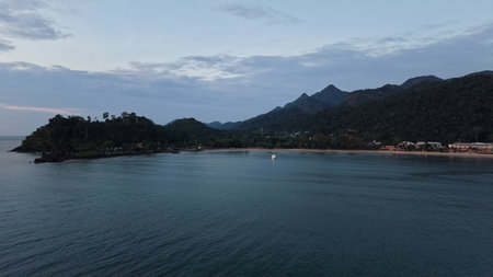 Tropical beach sunset illuminating clouds over distant mountainsの写真素材