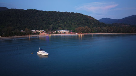 Motor yacht floating near tropical beach at dusk in thailandの写真素材