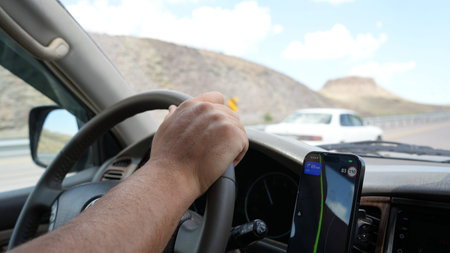 Driver using gps navigation on smartphone while driving car on mountain road