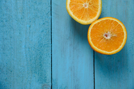 Fresh organic oranges halves fruits on blue wooden background with copy space
