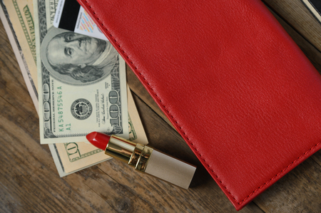 Workplace with red stylish leather wallet, money and lipstick on wooden table. Flat compositionの写真素材