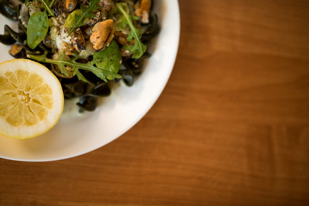 Black pasta with seafood in white cream sauce and lemonの写真素材