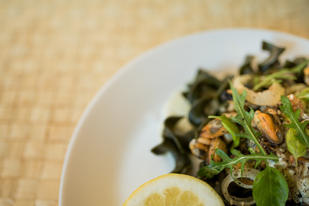 Black pasta with seafood in white cream sauce and lemonの写真素材