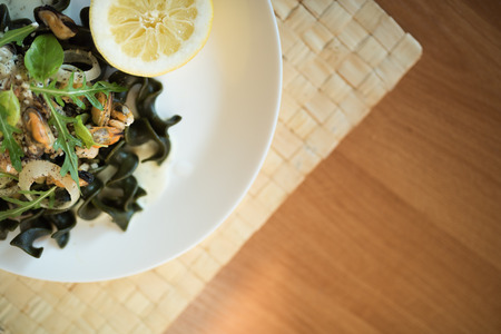 Black pasta with seafood in white cream sauce and lemonの写真素材