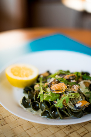 Black pasta with seafood in white cream sauce and lemonの写真素材