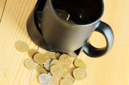 Broken mug and coins on a wooden tableの写真素材