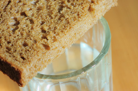 Glass of vodka and a slice of bread on a wooden table