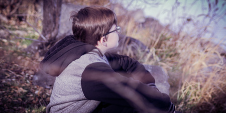 A boy sitting alone in the bushesの写真素材