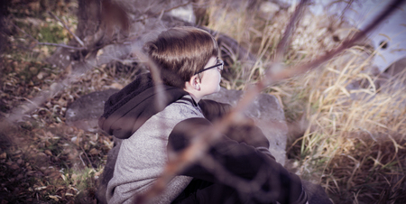 A boy sitting in the bushes looking at the viewの写真素材