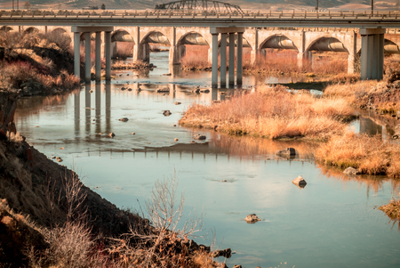 The Bear River on the other side of a closed dam is merely inches deep as winter approaches. Low water levels lead to interesting landscape below bridges and piping from the dam.の写真素材