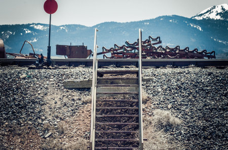 Metal stairs going up a gravel lined ditch allow workers to access the railroad tracks above.