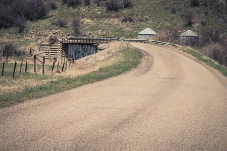 A country road crosses an interesting bridge in Idaho. The bridge becomes a narrow road with metal siding underneath and wooden retaining walls. The metal siding makes one wonder what it's covering up under the bridge.の写真素材