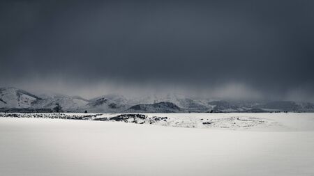 Dark clouds give way to snowfall in a rural snow-covered field during an Idaho Winter.の写真素材