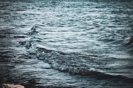The shimmering waves of the Alexander Reservoir as the last bit of light from the evening sun casts shadows and luminosity on bubbles and motion.の写真素材