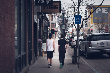 Two teenage boys walk along the sidewalk among the city shops in Old Town Pocatello, Idaho.のeditorial素材