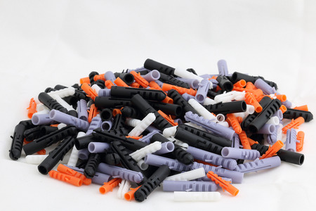 Wall plug - also known as screw anchor or dowel, in different colors and sizes on one pile, isolated on white, plastic toolの写真素材