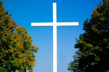 Large white wooden cross, with a bright blue sky 