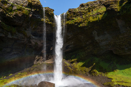 Stunning Rainbow Arcs Over Majestic Icelandic Waterfallの写真素材