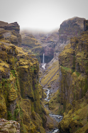 Stunning mountains with cascading waterfalls flowing through the lush MÃºlagljÃºfur Canyon in Iceland's rugged landscapeの写真素材