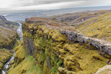 Stunning mountains with cascading waterfalls flowing through the lush MÃºlagljÃºfur Canyon in Iceland's rugged landscapeの写真素材