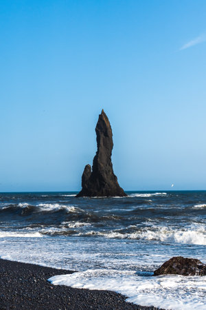 The dramatic Reynisfjara Beach features black volcanic sands and towering basalt sea stacks rising from the wild Atlantic Ocean in Icelandの写真素材