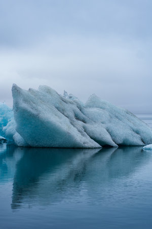 A breathtaking view of JÃ¶kulsÃ¡rlÃ³n Glacier Lagoon with floating icebergs and the contrasting black sands of Diamond Beach in Iceland, under a dramatic sky.の写真素材