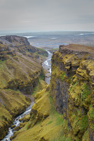 Stunning mountains with cascading waterfalls flowing through the lush MÃºlagljÃºfur Canyon in Iceland's rugged landscapeの写真素材