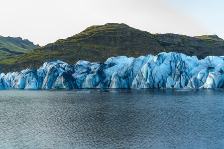 SÃ³lheimajÃ¶kull Glacier stretches down from the mountains into a serene lake, showcasing Iceland's stunning icy landscapeの写真素材