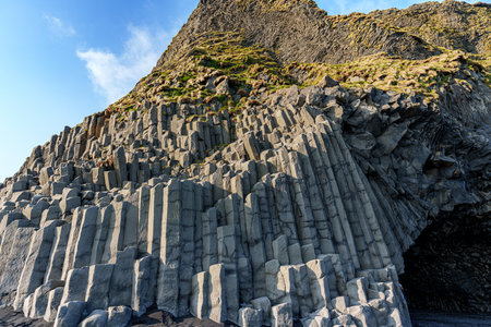 The dramatic Reynisfjara Beach features black volcanic sands and towering basalt sea stacks rising from the wild Atlantic Ocean in Icelandの写真素材