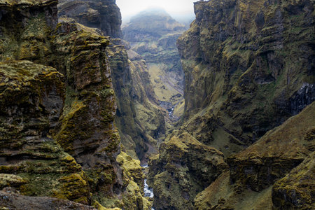 Stunning mountains with cascading waterfalls flowing through the lush MÃºlagljÃºfur Canyon in Iceland's rugged landscapeの写真素材