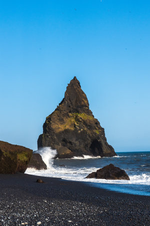 The dramatic Reynisfjara Beach features black volcanic sands and towering basalt sea stacks rising from the wild Atlantic Ocean in Icelandの写真素材